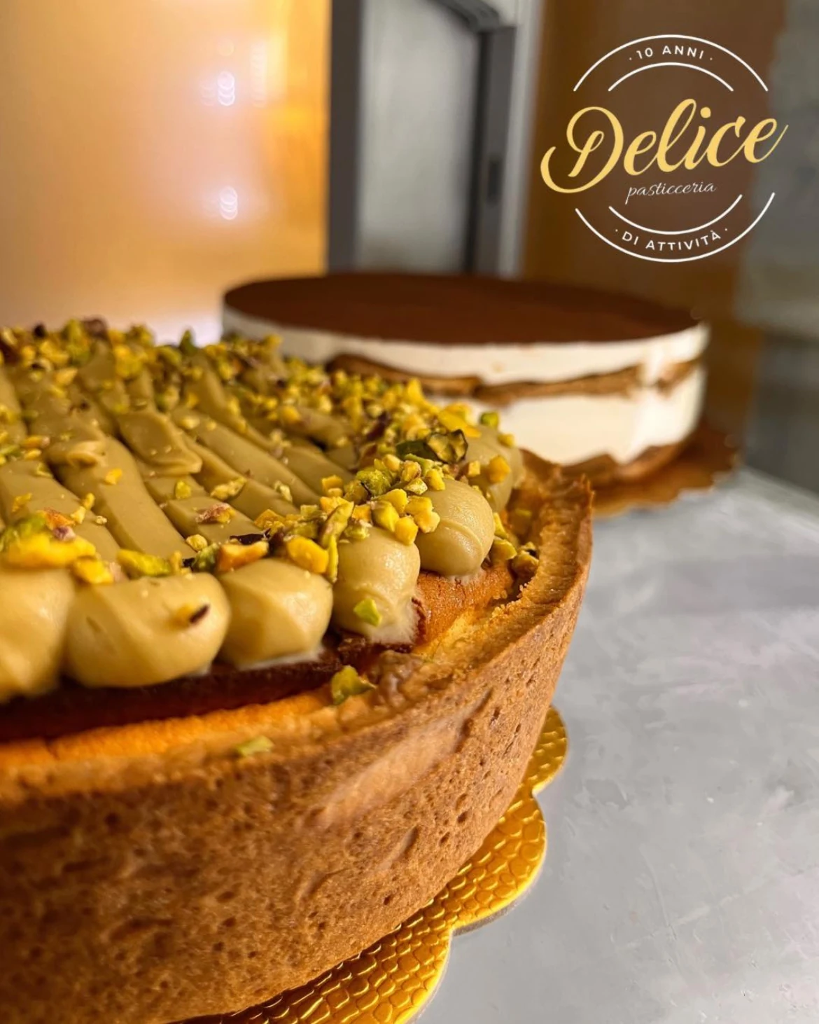 Torta al pistacchio Delice con granella e torta a strati sullo sfondo